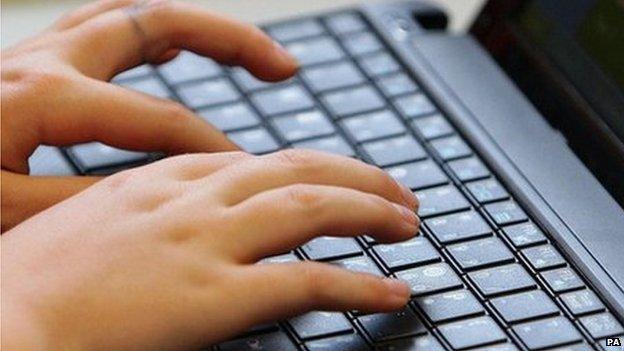 A young teenager types on a computer keyboard