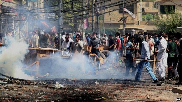 Supporters of an anti-Taliban cleric hurl stones toward policemen during clashes in Lahore, Pakistan, 17 June 2014