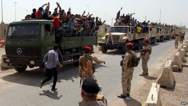 Iraqi men who volunteered to join the fight against ISIS's offensive run on board army lorries outside a recruitment centre in Baghdad (13 June 2014)