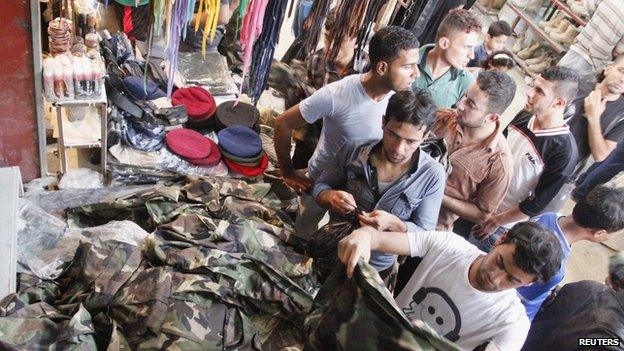 Iraqi men buy military uniforms at a shop in Basra, southeast of Baghdad, June 16