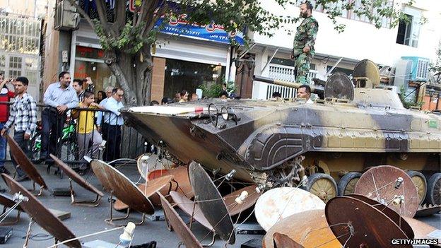 Iran security forces use an armoured vehicle to destroy satellite dishes