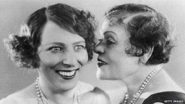 Woman whispering in other woman's ear