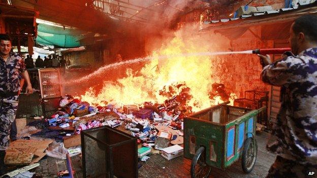 Members of the Palestinian Civil Defence hose down a shop that caught on fire due to clashes between Palestinians and Israeli soldiers in the West Bank city of Jenin on 19 June 2014.