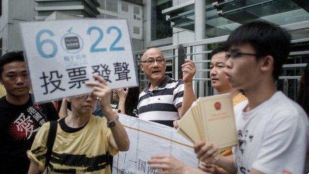 Demonstrators supporting the Occupy Central movement display placards asking residents to cast ballots for the 22 June during a protest outside Beijing's representative office in Hong Kong, on 11 June.