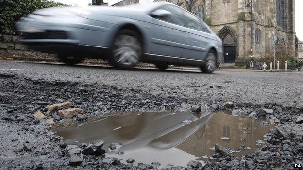 A car driving past a pothole