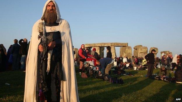 A modern druid named Merlin stands as the sun rises at the prehistoric monument Stonehenge