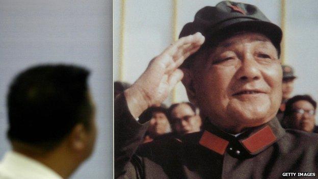 A man looks at a portrait of former Chinese leader Deng Xiaoping