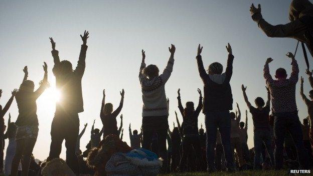 Revellers perform yoga as they celebrate the summer solstice