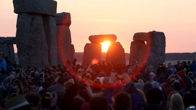 Revellers watch as the sun rises over the standing stones at the prehistoric monument Stonehenge