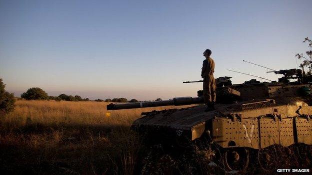 An Israeli soldier prays on a Merkava tank on the Israeli-Syrian border near Quneitra in the Golan Heights, 22 June 2014