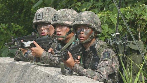 South Korean soldiers take position during a search and arrest operation as troops stand-off with a conscript soldier who shot and killed five comrades in South Korea, on 23 June 2014.