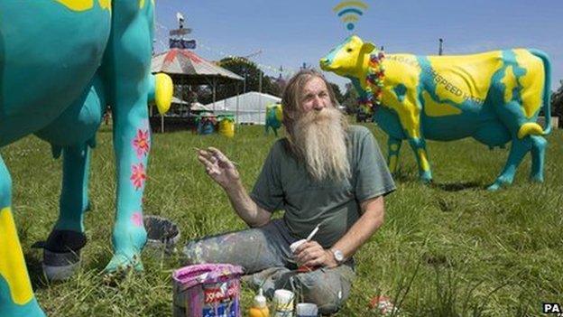 Artist Hank Kruger putting the finishing touches to a herd of fibreglass cows at Glastonbury festival.