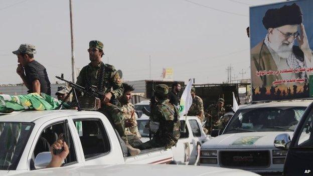 Armed Iraqi Shia militiamen parade through the city of Basra with a poster showing Iran's Supreme Leader, Ayatollah Ali Khamenei (14 June 2014)