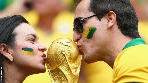 Brazil fans kiss a replica of the World Cup trophy at the Estadio Nacional during the Brazil v Cameroon game