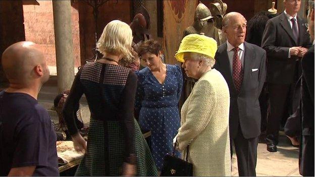 The Queen was shown some of the props and costumes which feature in the fantasy series during her visit to the Paint Hall Studios