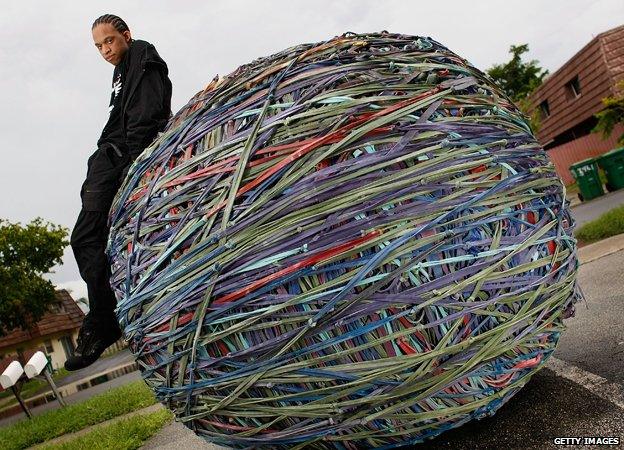 Joel Waul, 27, poses for a photograph with the rubber band ball that he created in the driveway of his home August 14, 2008 in Lauderhill, Florida