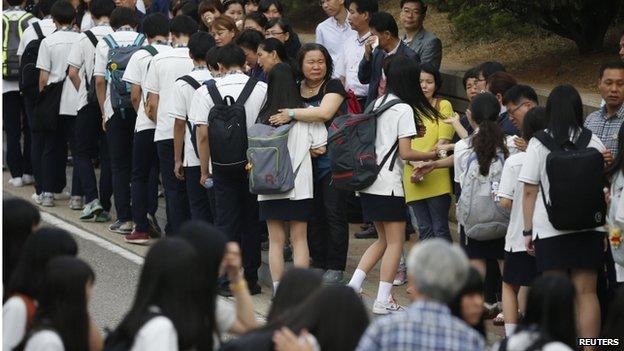 Relatives of the 16 April ferry disaster victims comfort students who survived the accident as they make their way back to school in Ansanon 25 June 2014.