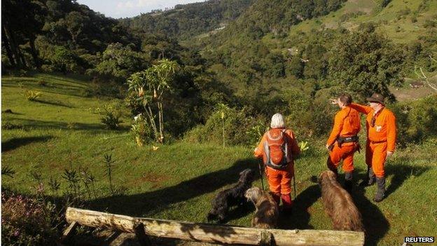 Sniffer dogs and members of independent Dutch rescue group Reddingshonden RHWW survey the landscape on a hiking trail during the second day of a search for two missing Dutch tourists in Boquete on 28 May, 2014.