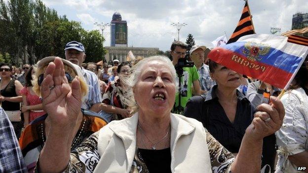 A woman waves a Russian flag as pro-Russia militants take the military oath of allegiance to the so-called People"s Republik of Donetsk