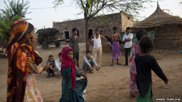 Girls walk through Indian village watched by young men