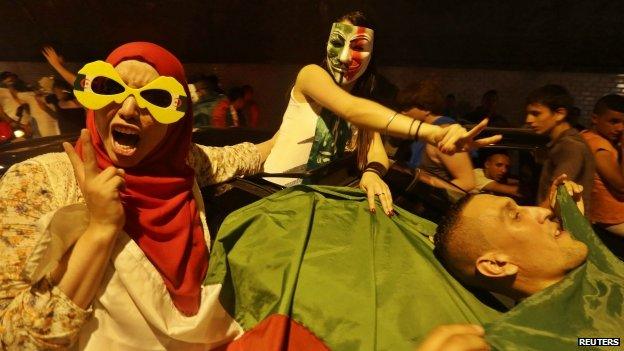 Football fans celebrate with an Algerian national flag after the end of Algeria's 2014 World Cup Group H match against Russia, in Algiers 26 June 2014.