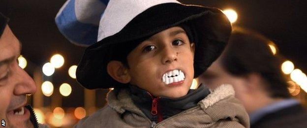 A child shows his support for Suarez by wearing plastic vampire's teeth at Carrasco International Airport near Montevideo