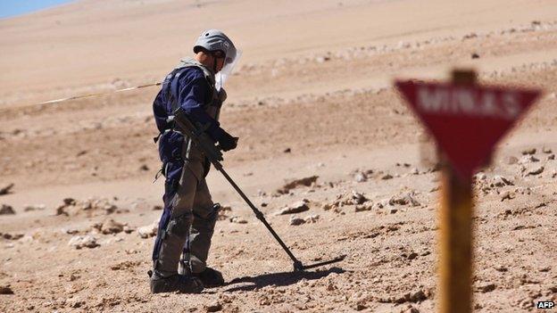 A Chilean army engineers wearing protective gear uses a magnetic detector in a minefield on 26 May 2014