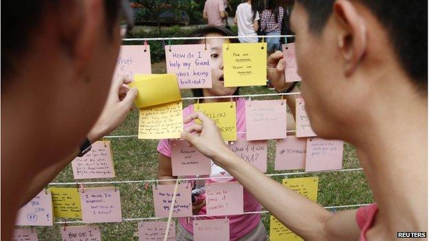 Participants dressed in pink read about issues of the Lesbian, Gay, Bisexual and Transgender (LBGT) community at a question-and-answer area where participants are free to write their questions and answers, before taking part in the forming of a giant pink dot at the Speakers" Corner in Hong Lim Park in Singapore on 28 June 2014.