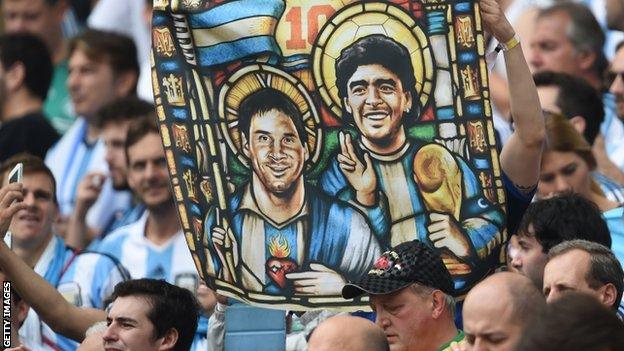 An Argentina fan holds an image of Argentina forward Lionel Messi and former footballer Diego Maradona as saints