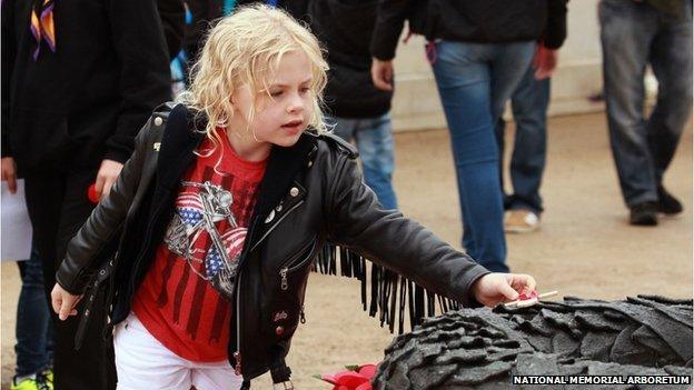 A child lays a poppy on a wreath