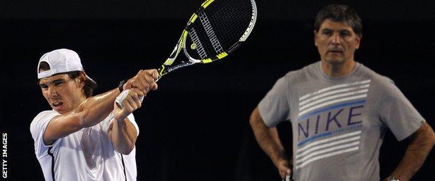 Rafael Nadal of Spain plays a backhand as he is watched by Toni Nadal, his uncle and coach.