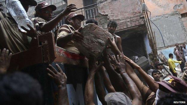 Rescuers load debris onto a lorry after the Delhi building collapse - 28 June