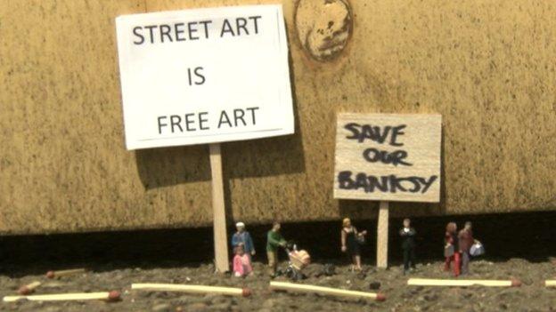 Signs next to Banksy artwork in Cheltenham