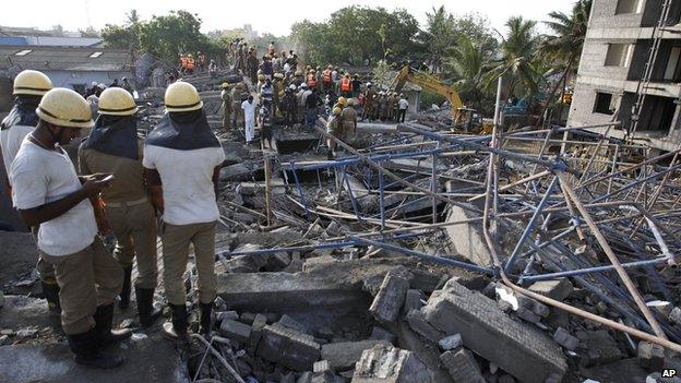 A rescuer, left checks his mobile phone as they search amid the rubble of a building that collapsed late Saturday during monsoon rains on the outskirts of Chennai, India, Sunday, June 29