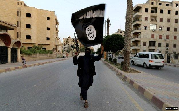 A gunman in the Syrian city of Raqqa waves an Isis flag - 29 June 2014