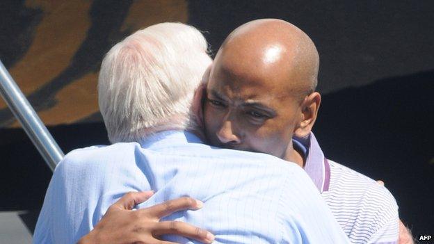 Former US President Jimmy Carter embraces Aijalon Mahli Gomes (R) on 27 August 2010 at Logan International Airport in Boston, Massachusetts