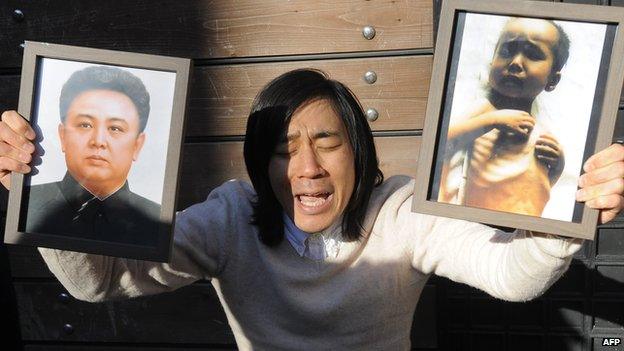 Robert Park holds photos of North Korean leader Kim Jong-Il (L) and a child suffering from malnutrition during a protest in front of the Chinese embassy in Seoul on 3 December 2010