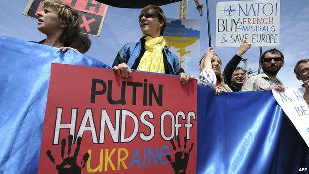 Protesters hold Ukrainian flags and placards during a demonstration in front of the French built Vladivostok warship being sold to Russia in Saint-Nazaire, western France (1 June 2014)