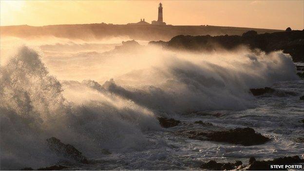 Stormy waves. Lighthouse in background