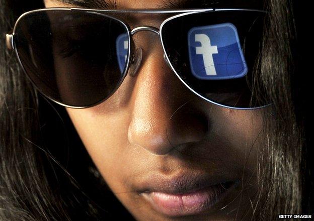 A woman with the Facebook logo reflected on her sunglasses