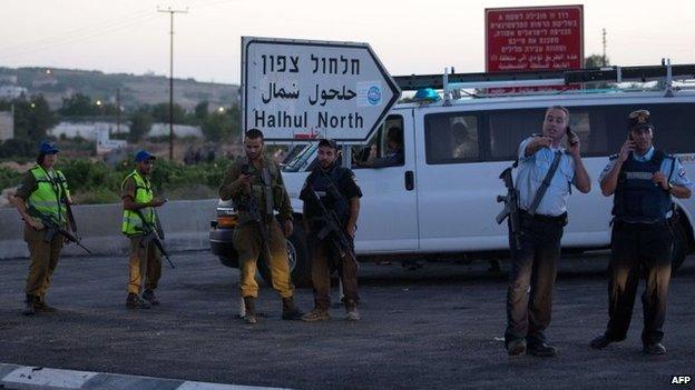 Israeli security forces speak on the phone as they stand guard on June 30