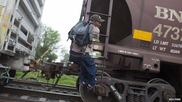 A migrant demonstrates to his friend (not pictured) how to catch a moving train in Atitalaquia, outskirts of Mexico City26 June 2014