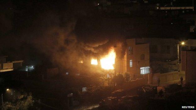 Flames and smoke are seen after a blast in the top floor of the family home of an alleged abductor in the West Bank City of Hebron, 1 July 2014