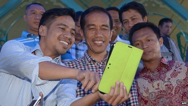 Indonesian men have their picture with presidential candidate Joko Widodo (centre) at a mosque as his entourage stops by for a prayer during his campaign in Jakarta on 30 June 2014.