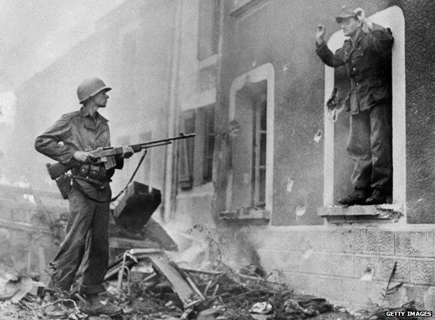 US soldier points a gun at German soldier