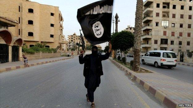 A gunman in the Syrian city of Raqqa waves an Isis flag - 29 June 2014