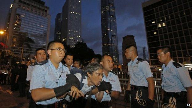 A protester, centre, is taken away by police offices after hundreds of protesters stage a sit-in overnight on a street in the financial district in Hong Kong, 2 July 2014