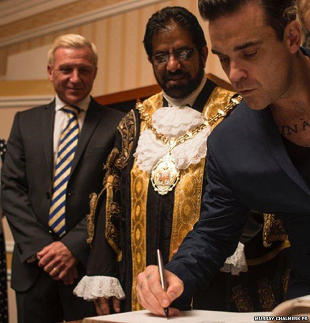 Robbie Williams signs the roll of honour