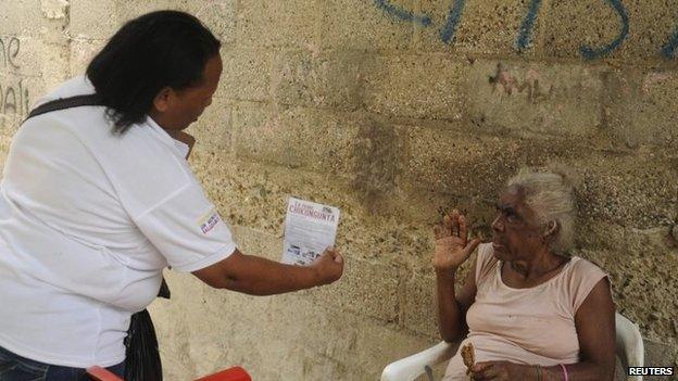 A health worker hands out a flyer about the Chikungunya virus in Santo Domingo on 23 May, 2014