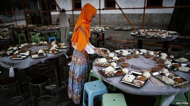 A woman distributes food on a table as she waits to break her fast in the Chinese capital Beijing